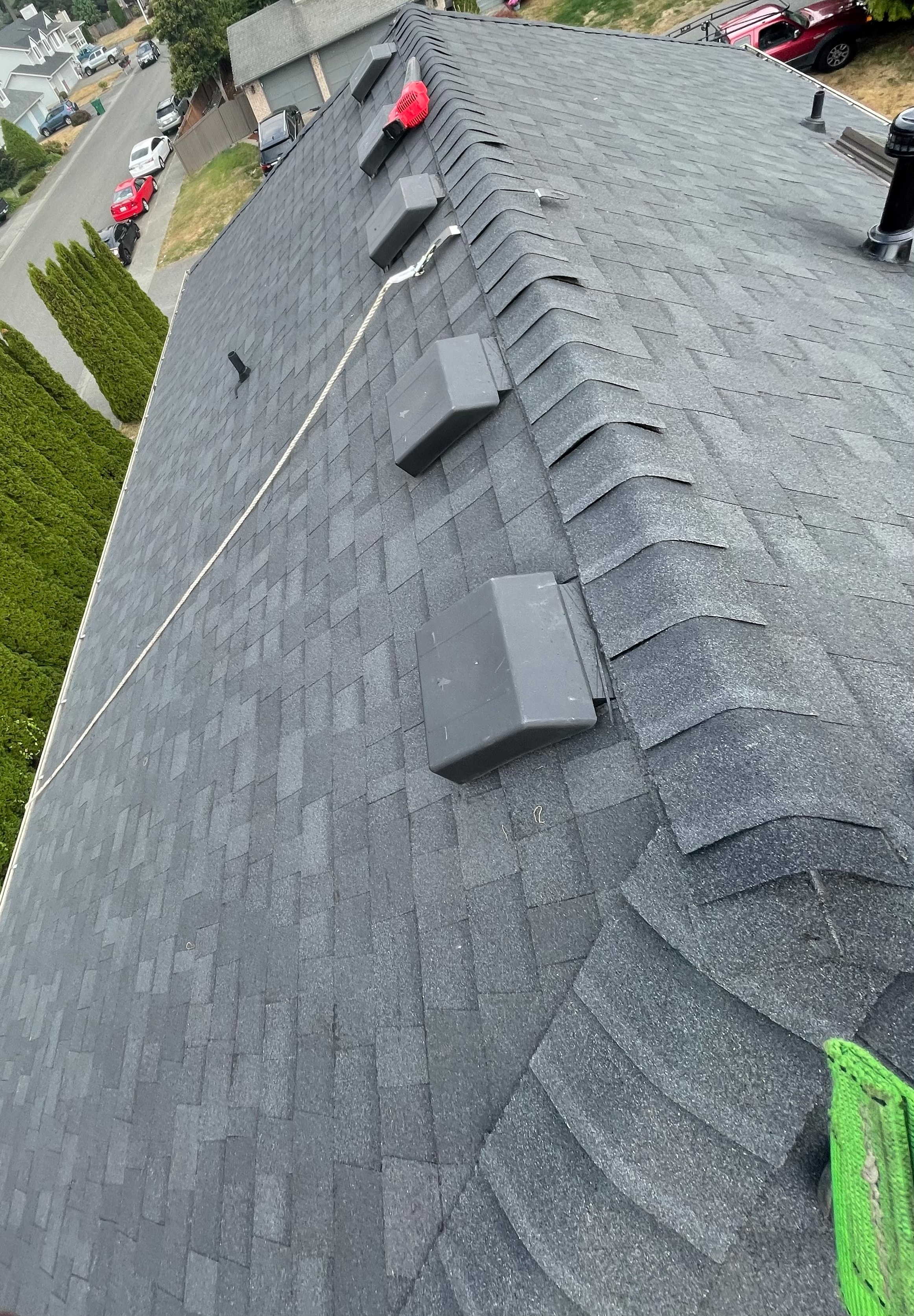 Aerial view of completed residential roof with grey architectural shingles and HVAC equipment on roof deck