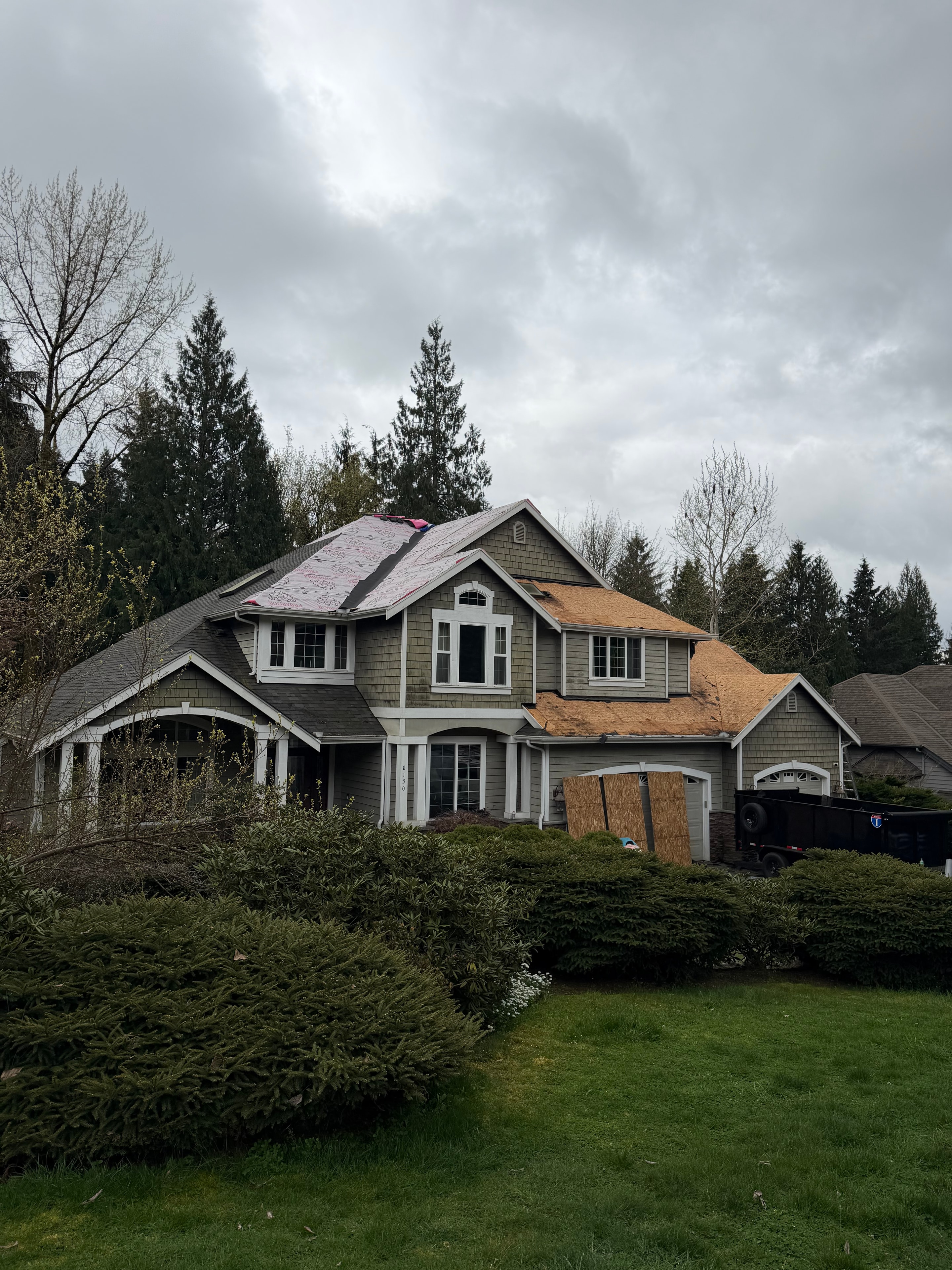 Residential roof mid-tearoff showing red felt underlayment and exposed decking during shingle replacement